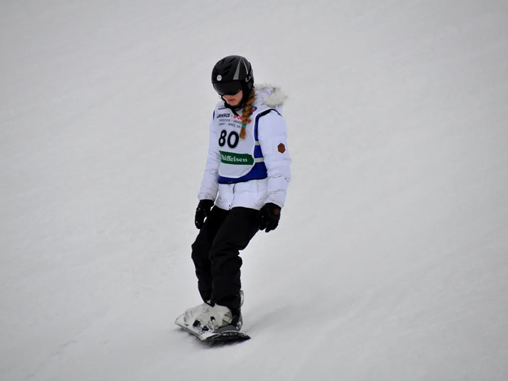 Snowboarderin mit Startnummer 80 in weißer Jacke.